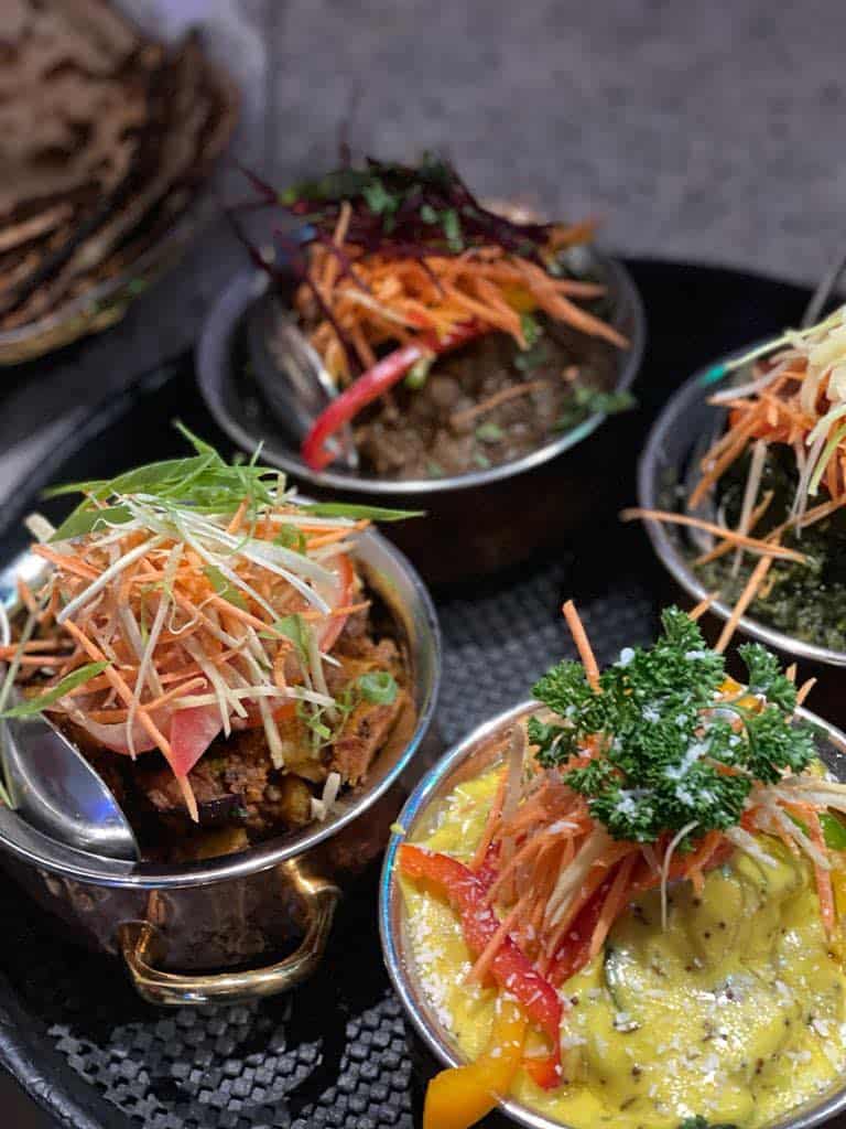 Fresh Asian-style salads with vibrant vegetables and herbs in small metal bowls.