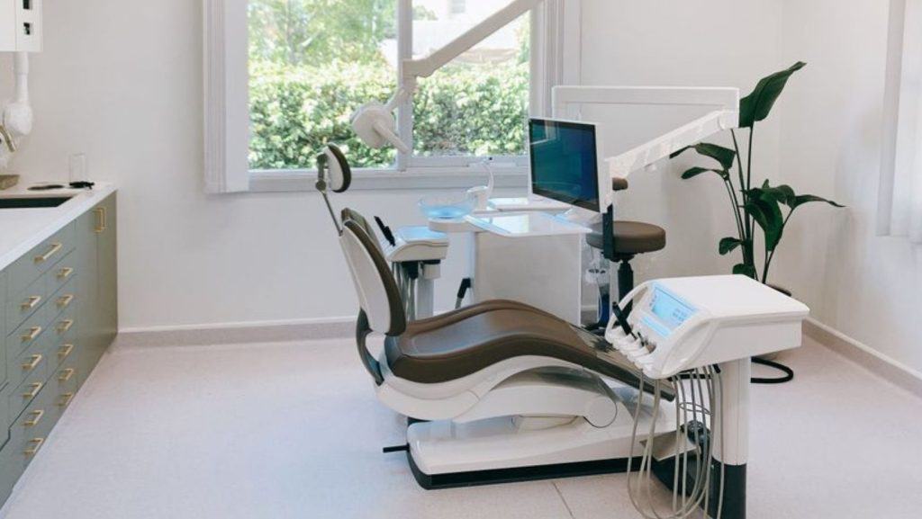 Modern dental clinic with dental chair and equipment in bright treatment room.