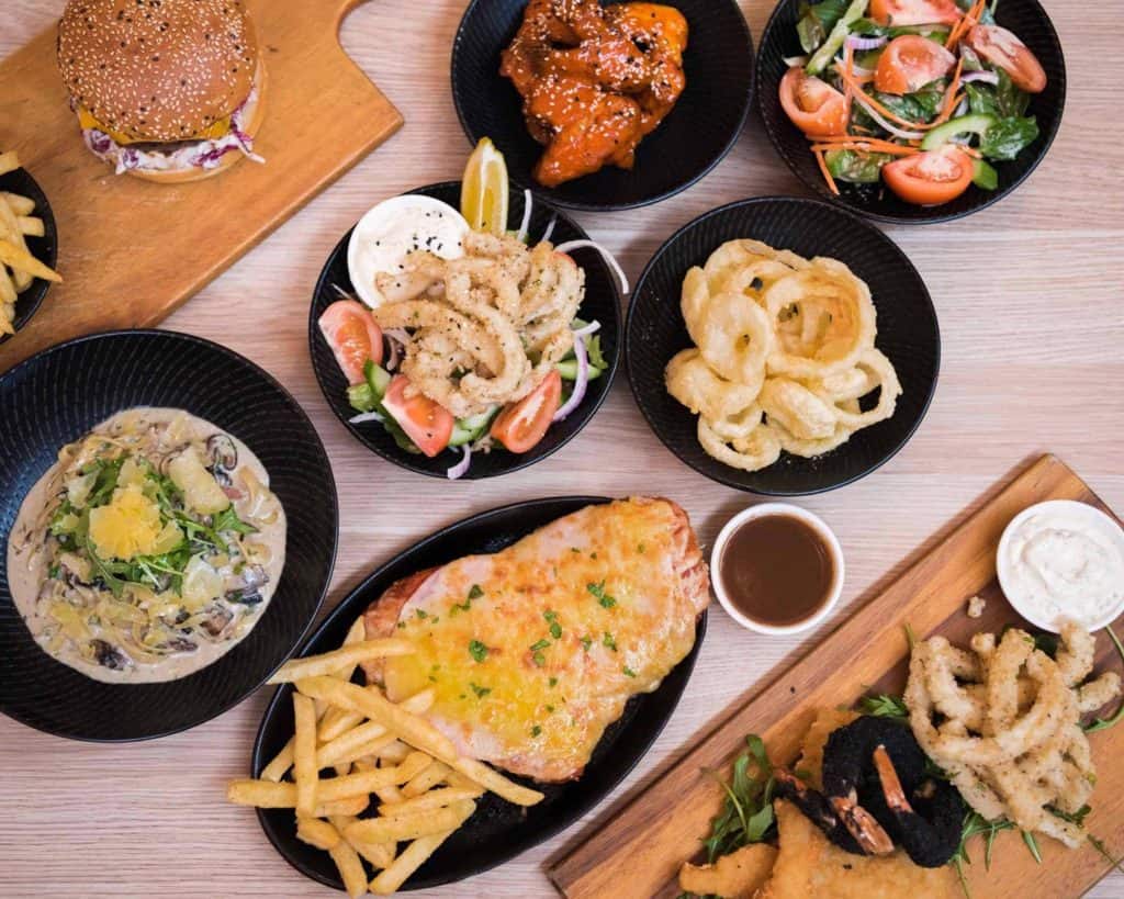 Delicious assorted dishes including fried calamari, chicken wings, sizzling steak, salad, burger, pasta, and seafood platter at Diamond Creek Shopping.