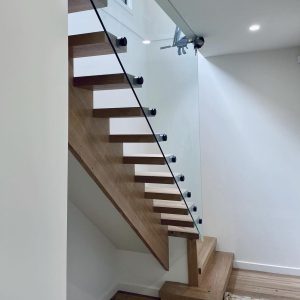 Sleek wooden staircase with glass balustrade at Diamond Creek Shopping.