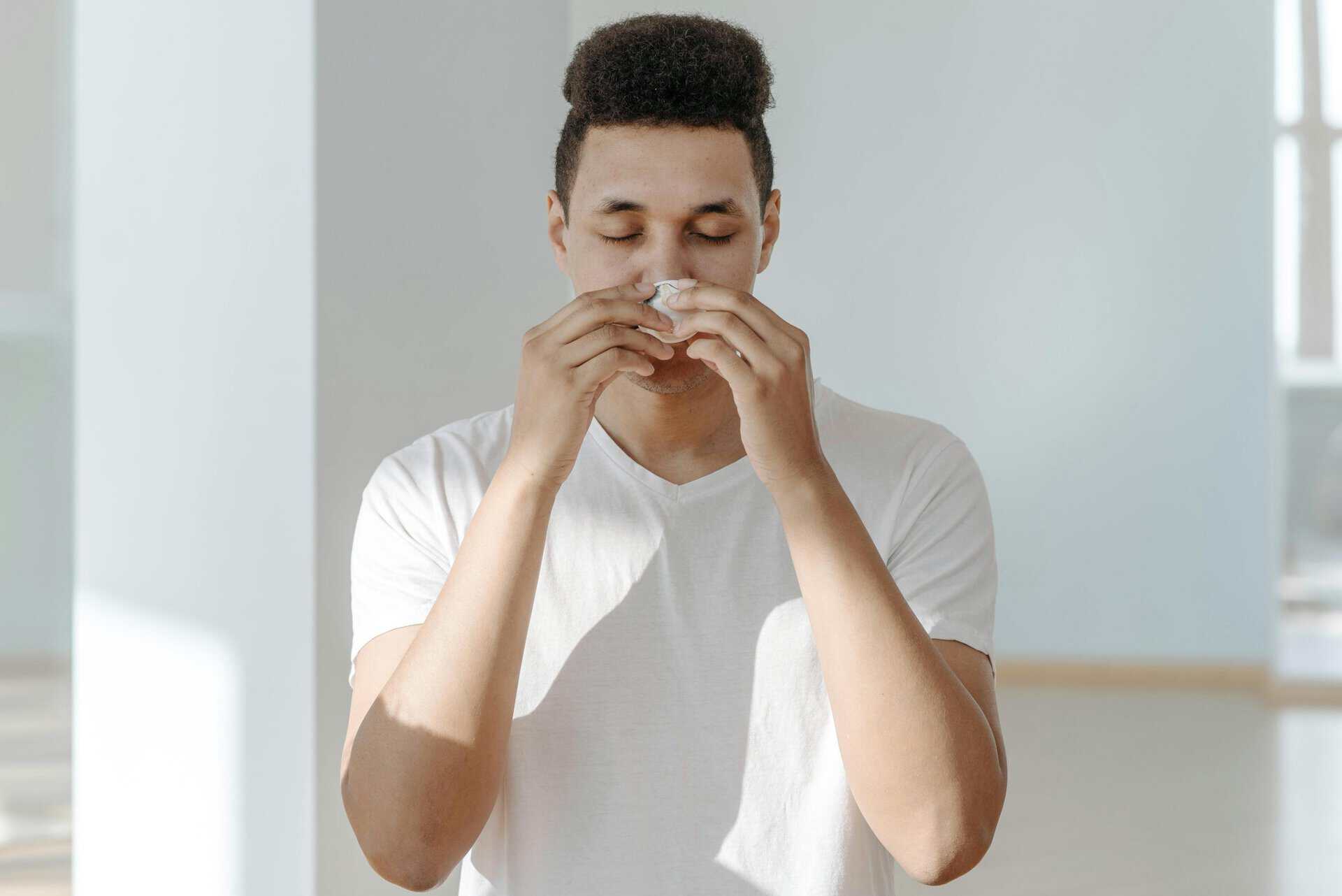 man wiping his nose with tissue