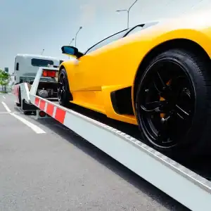 Yellow sports car being loaded onto a flatbed tow truck at Diamond Creek Shopping.
