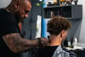 Barber cutting a customer's curly hair at Diamond Creek Shopping salon.