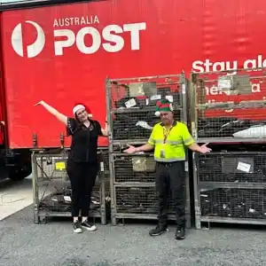 Australia Post staff celebrating Christmas at Diamond Creek with festive hats and delivery bins.