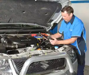 Mechanic checking car engine with diagnostic tools at Diamond Creek Shopping.
