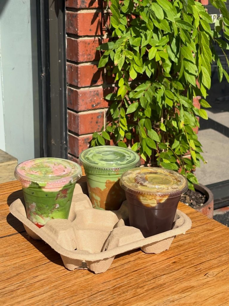 Freshly brewed iced coffee and matcha drinks on a wooden table outside Diamond Creek Shopping, Austr.