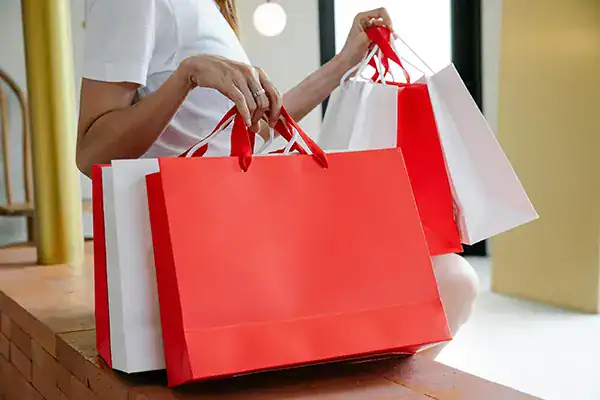 Woman holding red and white shopping bags at Diamond Creek Shopping mall.