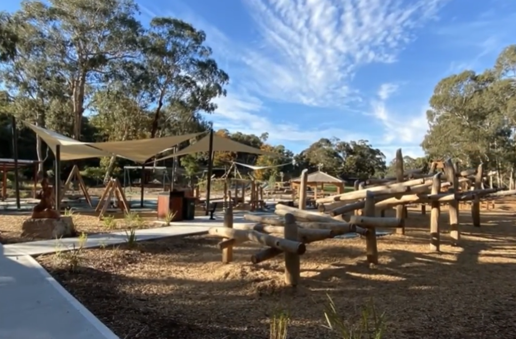 Outdoor kids playground with wooden structures and shade sails in Diamond Creek.