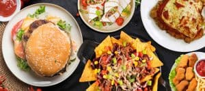 Assorted American fast food including burger, nachos, tacos, and chicken nuggets.