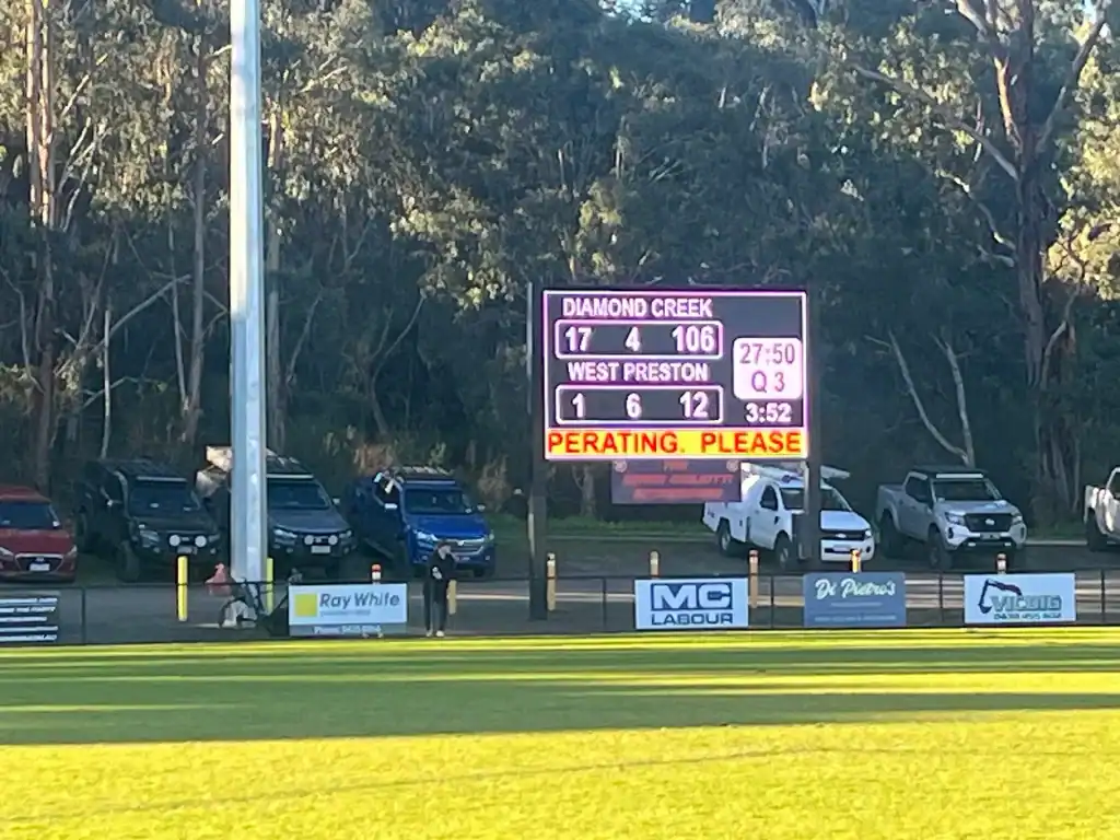 Scoreboard at Diamond Creek Shopping with game details and parked cars nearby.