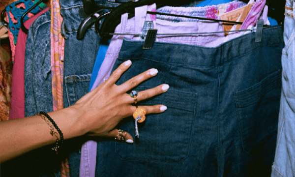 Person browsing second-hand jeans at Diamond Creek Shopping thrift store.