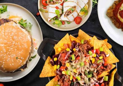 Assorted American fast food including burger, nachos, tacos, and chicken nuggets.