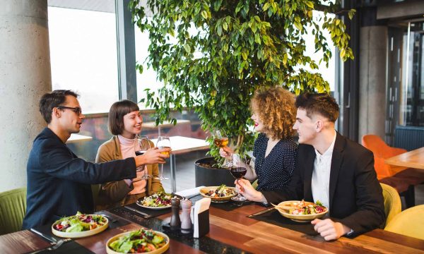 Group of friends enjoying a meal at Diamond Creek Shopping restaurant with fresh salads and drinks.