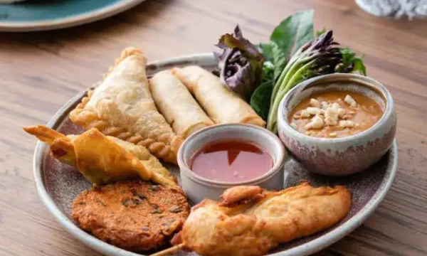 Delicious Asian appetizer platter with spring rolls, samosas, and dipping sauces at Diamond Creek Sh.