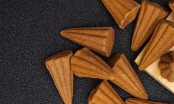 Close-up of brown cone-shaped incense on black background.